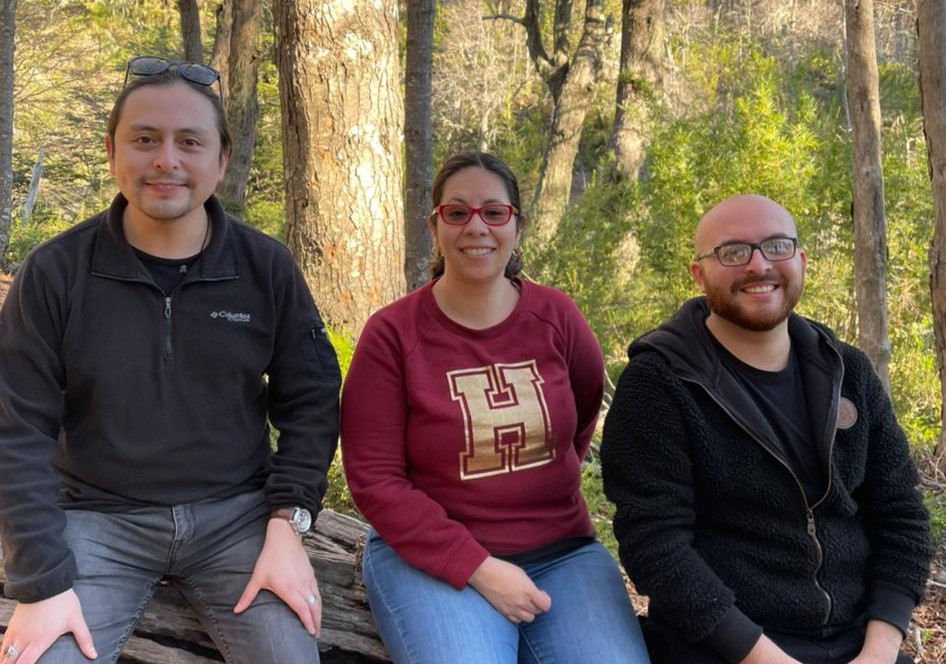Image of three individuals smiling in the woods