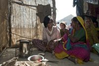 Women chatting in a hut, clean cookstoves, children smiling