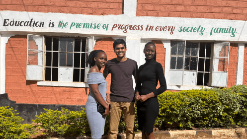 Photo of Duke student with two Kenyan colleagues during 2022 internship; background text "education is the premise of progress in every society, family."