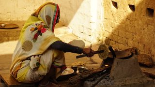 a woman in a yellow and white sari is making food